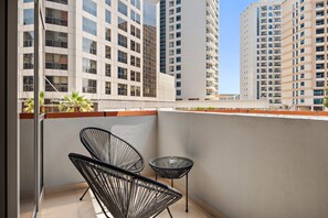 A balcony with two black wire-framed chairs and a small round table, overlooking a cityscape with tall residential buildings. - Silkhaus Near Metro Art XII Tower Pool Gym (Dubai)