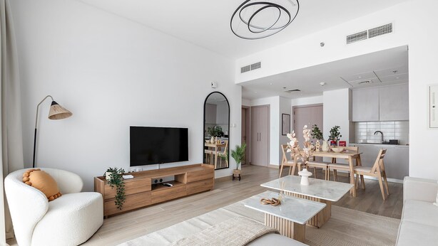 En moderne stue med TV, sofa, sofabord og spiseplads.