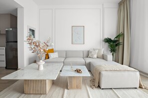 A modern living room with a sofa, two coffee tables, and a decorative plant. - Silkhaus 1bdr in Water s Edge Access to Canal (Abu Dhabi)