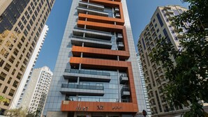 Een modern hoog gebouw met een restaurant op de begane grond, omringd door andere hoge gebouwen.
