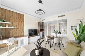 A modern living room with a dining area, a kitchen, and a TV. - Silkhaus Canalside 1BR Water s Edge Yas Island (Abu Dhabi)