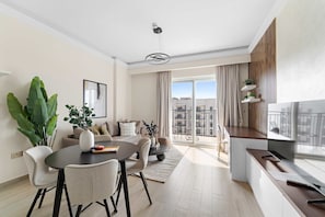A modern living room with a dining area, large windows, and a balcony. - Silkhaus Canalside 1BR Water s Edge Yas Island (Abu Dhabi)