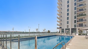 A rectangular swimming pool with clear blue water, surrounded by a tiled deck. - Silkhaus in Water s Edge Close to Ferrari World (Abu Dhabi)