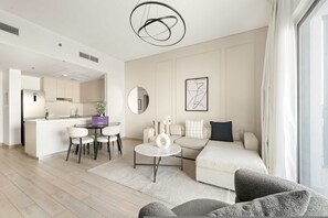 A modern living room with a sofa, a round coffee table, and a dining area with chairs. - Silkhaus in Water s Edge Close to Ferrari World (Abu Dhabi)