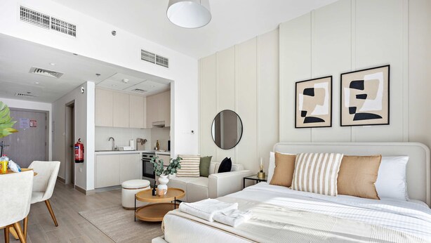 A modern hotel room with a large bed, a dining area, and a kitchenette. - Silkhaus Canal View Studio Near Ferrari World (Abu Dhabi)