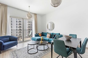 Ein modernes Wohnzimmer mit einer Couch, zwei Sesseln, einem Couchtisch und einem Esstisch.