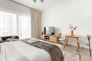A hotel room with a bed, a TV, a desk, and chairs. - Silkhaus Canalside Studio in Water s Edge Tower (Abu Dhabi)