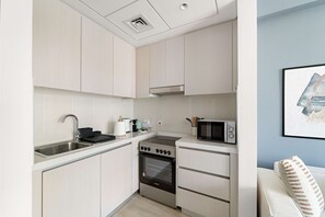 Une cuisine moderne avec des meubles de couleur claire, un évier en acier inoxydable, une cuisinière et un four à micro-ondes.