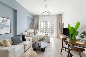 A modern living room with a sofa, coffee table, and dining area. - Silkhaus Canalside Cozy Studio Water s Edge (Abu Dhabi)