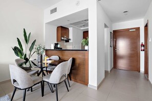 A modern kitchen with a central island, a dining area with four chairs, and a wooden door. - Silkhaus Urban 1BR Stay ARC Tower in Reem Island (Abu Dhabi)