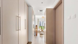 A modern hallway with light wooden flooring, a central rug, and a view into a living area with a sofa and a coffee table. - Silkhaus Chic Studio Yas Island Near Sea World (Abu Dhabi)