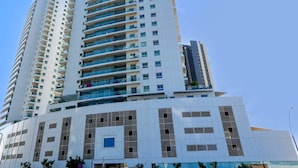 A high-rise building with multiple floors, large windows, and balconies. - Silkhaus Premium 1BR at Amaya Tower in Reem Island (Abu Dhabi)