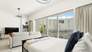 A modern hotel room with a large bed, a sofa, a TV, and a view of a cityscape through floor-to-ceiling windows. - Silkhaus Modern Studio Arc Tower Reem Island (Abu Dhabi)