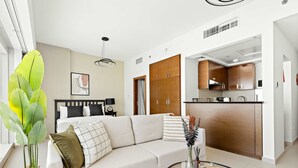 A modern living room with a sofa, a coffee table, and a large plant. - Silkhaus Modern Studio Arc Tower Reem Island (Abu Dhabi)