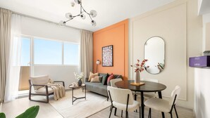 Een moderne woonkamer met een bank, stoelen, een eettafel en een groot raam.
