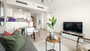 Een moderne woonkamer met een bank, een salontafel, een televisie en een eetgedeelte met stoelen en een tafel.