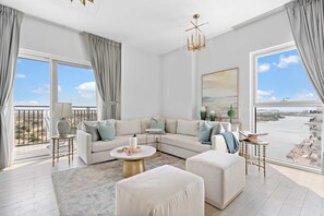A modern living room with a large sofa, a coffee table, and a view of the sea through large windows. - Silkhaus Lavish 3BR Maid Yas Island (Abu Dhabi)