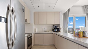A modern kitchen with light wood cabinets, stainless steel appliances, and a view of the sky through a large window. - Silkhaus Lavish 3BR Maid Yas Island (Abu Dhabi)