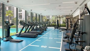 Un gimnasio con cintas de correr, máquinas de pesas y una zona de piscina.