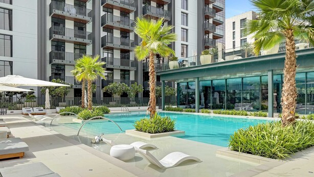 Un hotel moderno con piscina, tumbonas y palmeras.