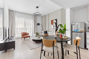 Ein modernes Wohnzimmer mit Essbereich, einer Couch, einem Couchtisch und einem Fernseher.