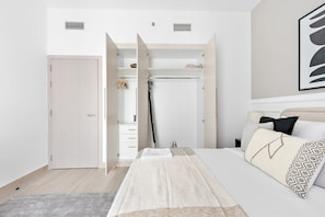 Ein Schlafzimmer mit Bett, Kleiderschrank und einem durchgegangenen Tür sichtbaren Badezimmer.