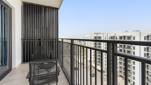 Ein Balkon mit schwarzem Metallgeländer, einem schwarzen Metallstuhl und einem Tisch.