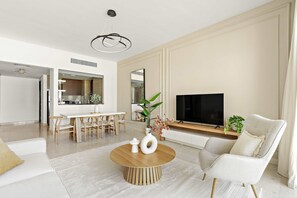 Ein modernes Wohnzimmer mit rundem Couchtisch, einer Sitzecke und einem Essbereich mit Holzmöbeln.