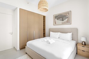 Une chambre moderne avec un grand lit, une armoire, une table de chevet avec une lampe et un luminaire suspendu.