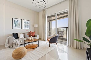 A modern living room with a sofa, armchair, coffee table, and a large window with curtains. - Silkhaus Premier 2BR Apartment in Marina Bay (Abu Dhabi)