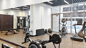 Uma academia com máquinas de remo, esteiras e bolas de exercício.