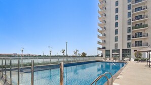 Una piscina rectangular con agua azul cristalina, rodeada por un deck con baldosas.