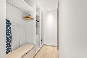 A walk-in closet with open shelving, a hanging rack, and a bench. - Silkhaus Canal View 3bdr Maid Near Ferrari World (Abu Dhabi)