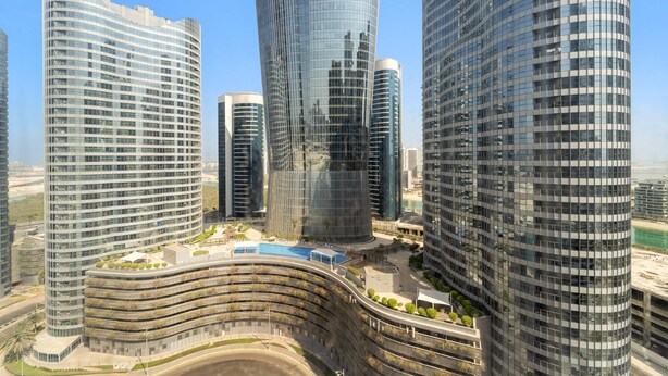 A modern urban skyline with high-rise buildings featuring curved glass facades and a central plaza with a pool. - Silkhaus Elite 1bdr Stay in New Radiant Viewz Tower (Abu Dhabi)