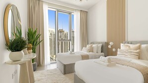 Une chambre d’hôtel moderne avec deux lits, une grande fenêtre donnant sur la ville, un miroir rond et une plante en pot.