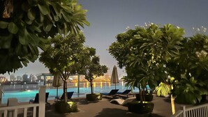 Un espace aménagé au bord de la piscine, avec des chaises longues et des parasols, entouré d’une végétation luxuriante.