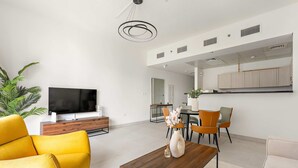 A modern living room with a sofa, coffee table, TV, and dining area. - Silkhaus Executive 1bdr Reem Island Najmat (Abu Dhabi)