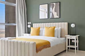 A modern bedroom with a large bed, two bedside tables, a nightstand, and a view of the outdoors. - Silkhaus Najmat Tower Luxurious 1bdr Park Access (Abu Dhabi)