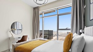 Habitación de hotel moderna con una cama grande, un escritorio y vista a la playa.