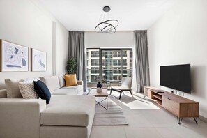 A modern living room with a sofa, coffee table, TV stand, and a large window with a view of buildings. - Silkhaus Large 2bdr in Najmat Near Reem Park (Abu Dhabi)
