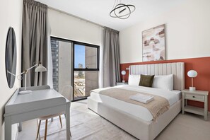 A hotel room with a bed, desk, chair, bedside tables, and a view through a large window. - Silkhaus Large 2bdr in Najmat Near Reem Park (Abu Dhabi)