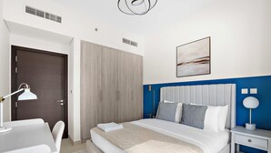Un dormitorio con cama, mesita de noche, escritorio, silla, armario y una obra de arte en la pared.