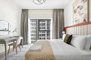 A hotel room with a bed, a desk, a chair, a large window, and a view of buildings outside. - Silkhaus Large 2bdr in Najmat Near Reem Park (Abu Dhabi)