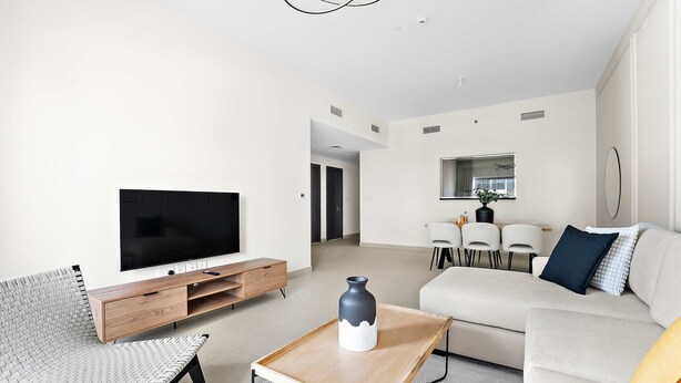 Una sala moderna con televisor de pantalla plana, un sofá, una mesa de centro y un comedor con sillas y una mesa.
