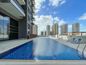 Ein Pool auf dem Dach mit freiem Blick auf umliegende Hochhäuser.