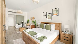 A modern bedroom with a large bed, bedside tables, a desk, and chairs. - Silkhaus Studio on Palm New Modern Sea View (Dubai)