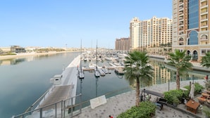 A marina with boats docked, a palm tree, and a building with balconies. - Silkhaus Studio on Palm New Modern Sea View (Dubai)