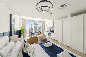 A modern hotel room with a bed, a sofa, a dining area, and a view of the city. - Silkhaus Comfy Studio Liberty House Difc Heart (Dubai)