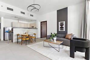 Un espai de vida modern amb cuina, zona de menjador i un sofà gris.