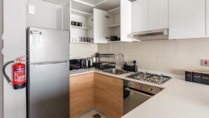 Eine moderne Küche mit einem Edelstahl-Kühlschrank, einem Gasherd und Holzschränken.